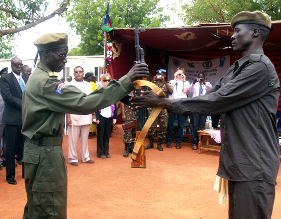 One of the ex-combatant (right) hands over a gun to an SPLA member (Left) as the SSDDRC officials witness [©Gurtong]
